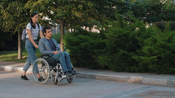 Woman Pushing a Man in a Wheelchair