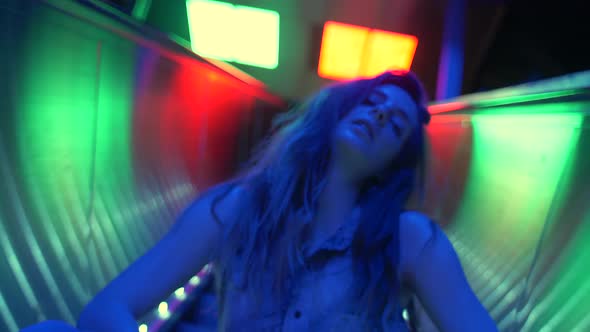 Young woman sitting on an escalator with neon lights