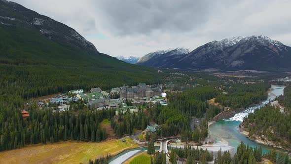 Aerial footage of massive hotel at the foot of the mountains near Bow River (Banff, Alberta, Canada)