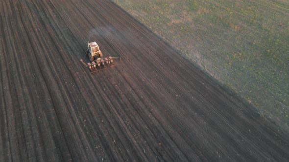 Aerial View of Farmer in Old Tractor Preparing Land with Seedbed Cultivator in Farmlands