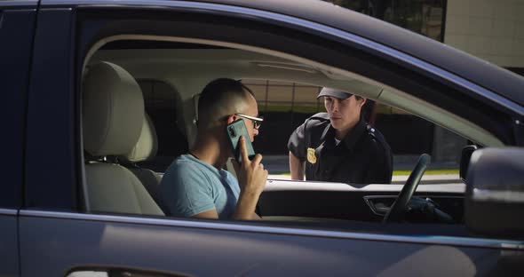 Irritated Driver with Smartphone Speaking with Police Officer