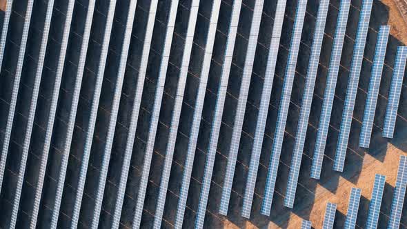 Sunset aerial view of solar panels stand in a row in the dark fields