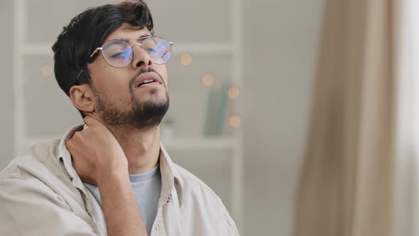 Portrait of Young Arabic Hispanic Indian Man Bearded Male Tired Guy with Glasses Holds Neck Ache
