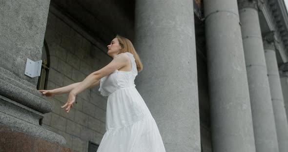 Young Balerine in White Dress Dances on the Stairs of the Theatre in Slow Motion Ballet Dancer Doing