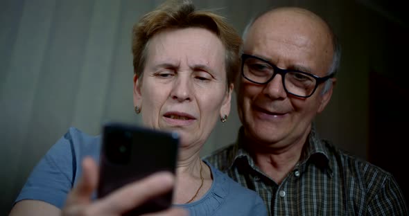 Elderly Woman and Man Is Examining New Smartphone