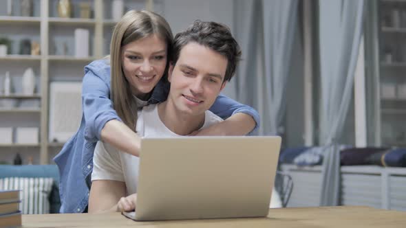 Happy Young Couple Selecting Things to Buy Online Using Laptop
