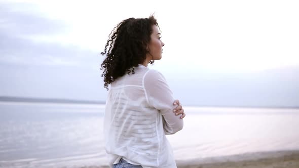 Close Up Side Footage of an Attractive Young Woman Walking By Seaside in Water Wearing a White Shirt