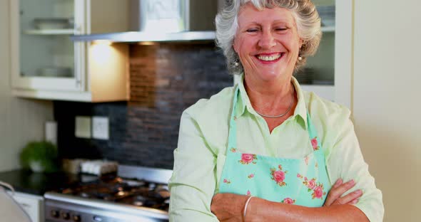 Senior woman standing with arms crossed in kitchen 4k