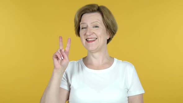 Victory Sign By Old Woman Isolated on Yellow Background