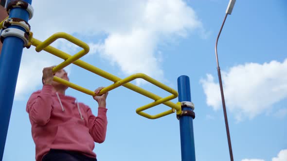 A Guy Performs a Pullup in a Street Training Park
