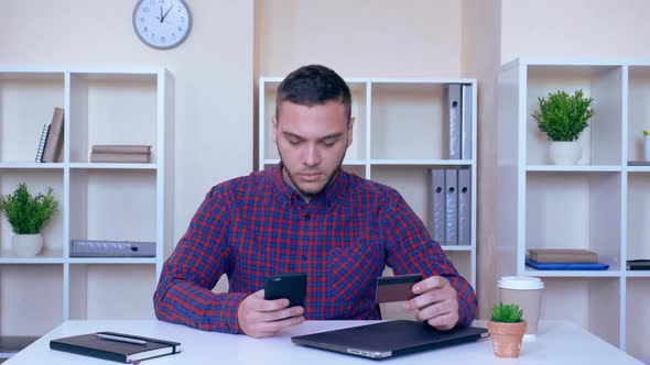 Businessman Sitting at the Working Place Pays Bill