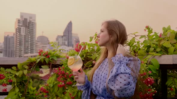 Woman on Rooftop Garden on Golden Hour Sunset with Glass of Alcohol Cocktail
