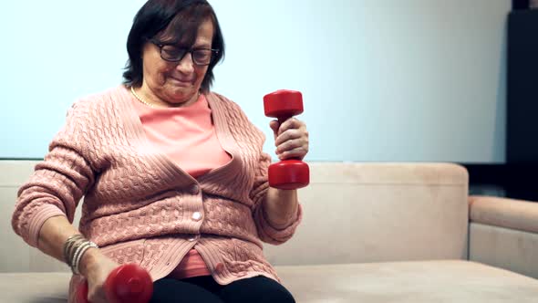 Old Granny Training Dumbbells On Home. Senior Woman Sport Workout Weight Lifting.