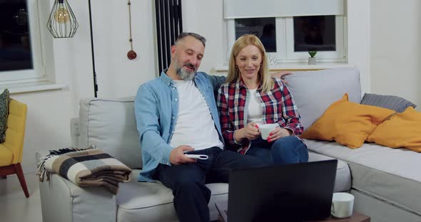 Couple which Sitting Together on Soft Couch in Living-Room and Talking