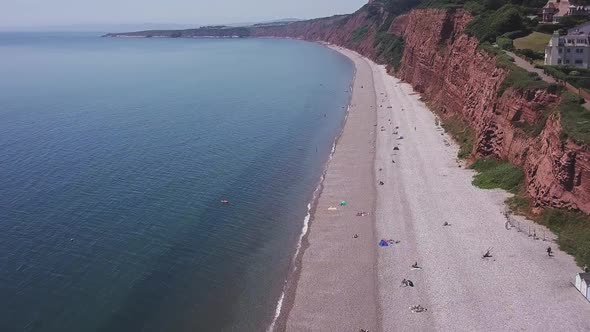 Aerial, flying over the beach alongside red cliffs in Budleigh Salterton, Jurassic Coast, STATIC CRO