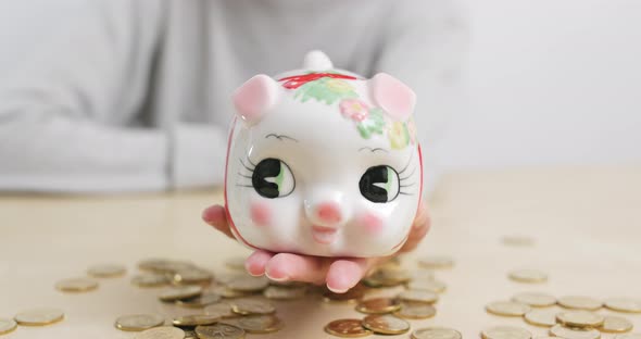 Woman putting coin in piggy bank