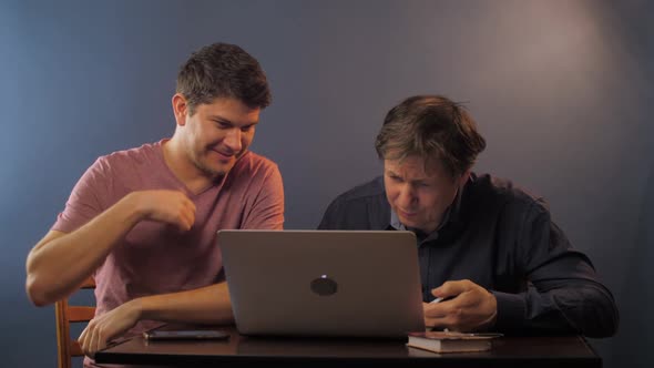 Happy Man Explains How Work with Laptop To Senior Colleague