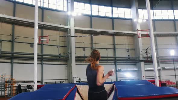 Pole Vaulting Indoors - a Young Woman with Ponytail Running Up and Jumping Over the Bar - Touches