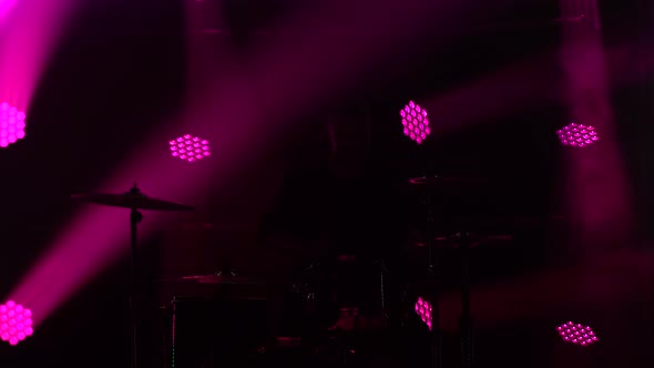 Silhouette Drummer Playing on Drum Kit on Stage in a Dark Studio with Smoke and Neon Lighting