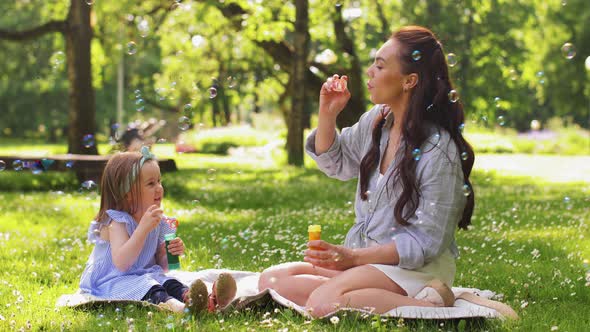 Mother with Daughter Blowing Soap Bubbles at Park