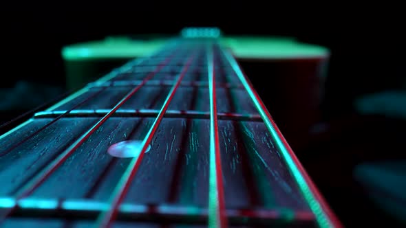 Fretboard of Classical Acoustic Guitar Against Black Background Illuminated By Blue and Red Light