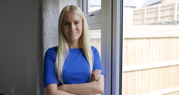 Smiling blond woman standing at window