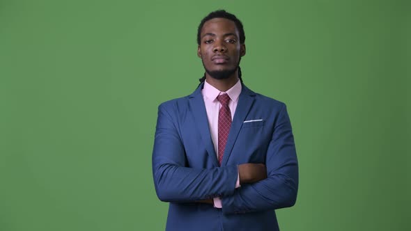 Young Handsome African Businessman with Dreadlocks Against Green Background