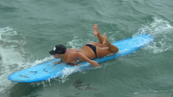 A young woman surfing in a bikini on a longboard surfboard.