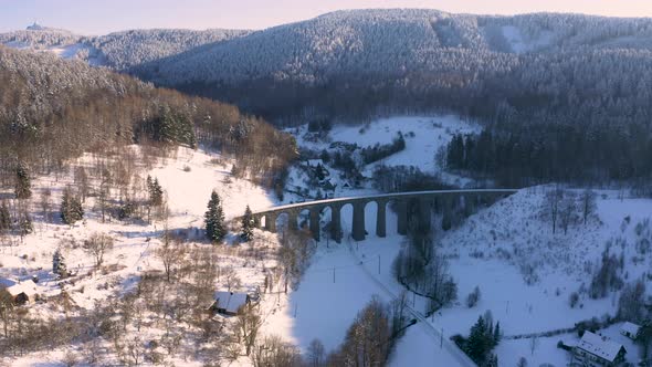 Aerial view of a stone train viaduct in a winter mountain valley,snow.