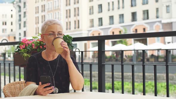 Beautiful Woman Is Drinking Coffee and Sending Messages at Street Cafe