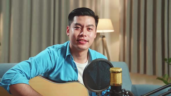 Asian Man Is A Vlogger With Guitar And Microphone Looking To Camera