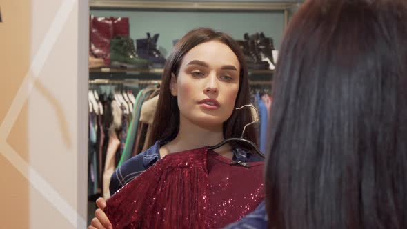 Attractive Woman Smiling To the Camera While Trying on a New Dress at the Store