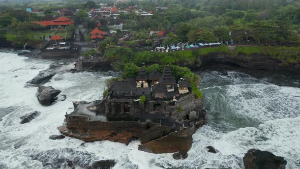 Tilting Aerial Shot Flying Away From Empty Tanah Lot Temple During Dangerous Weather in Bali