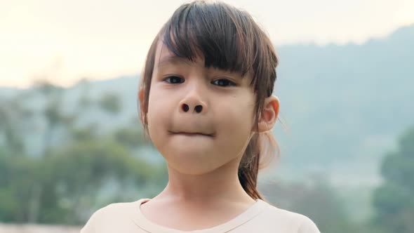 Portrait of a cute Asian preschooler smiling happily in the summer garden.