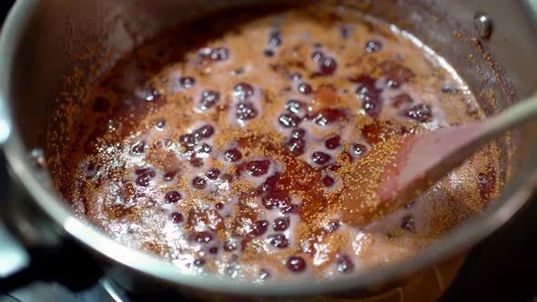 Crop person preparing fig jam in pressure cooker in kitchen