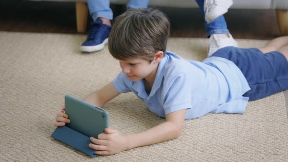 Boy Lying Using Digital Tablet