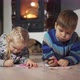 Brother and Sister Lying on the Floor in the Room Writing and Drawing Fireplace in the Background - VideoHive Item for Sale