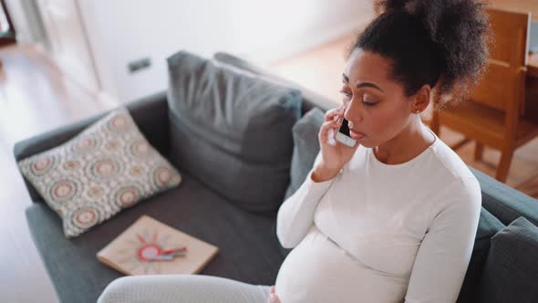 Overhead view of pretty African pregnant woman talking by phone