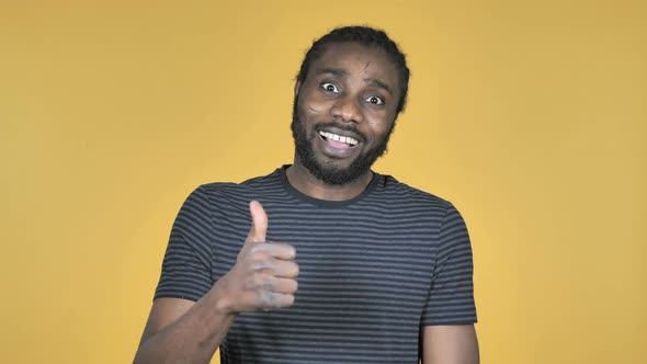 Casual African Man Gesturing Thumbs Up Isolated on Yellow Background