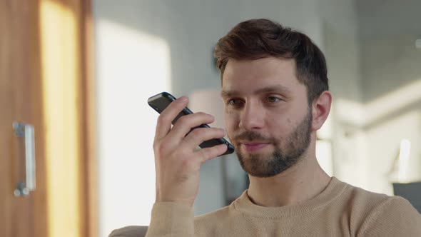 Attractive man recording an audio message on the phone