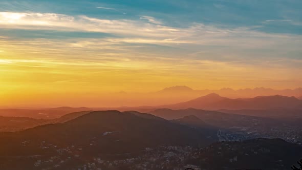 Moving clouds and colorful sky during golden hour just over the beautiful mountains. Static. Timelap