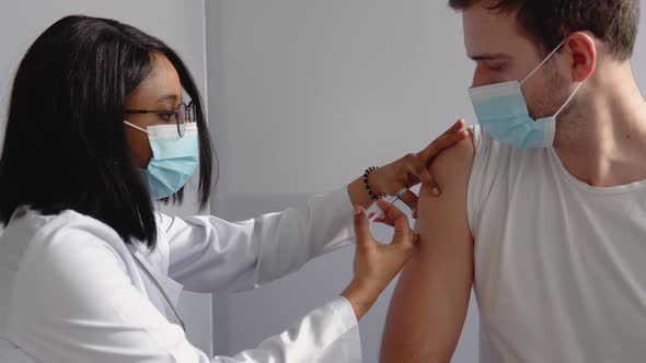 Young Indian Nurse Giving Covid19 or Flu Antivirus Vaccine Shot to Young Male Patient Wear Face Mask