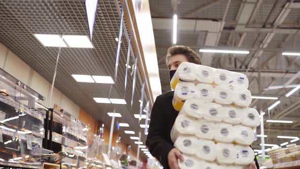 Man Walking in Medical Mask with Toilet Paper Shopping Bags During the Quarantine Coronavirus