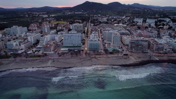 Reversing shot revealing the town of Cala Millor and the mountains in distance at dusk