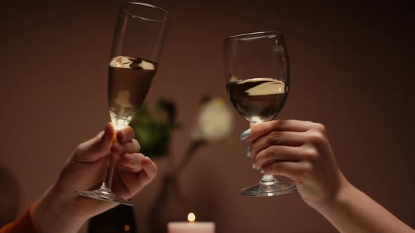 Closeup Hands of Unrecognizable Couple of Clinking White Wine Glasses During Romantic Dinner