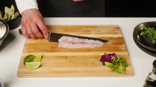 Professional Chef Putting Raw White Fish Fillet on Cutting Board Closeup Thin Slice