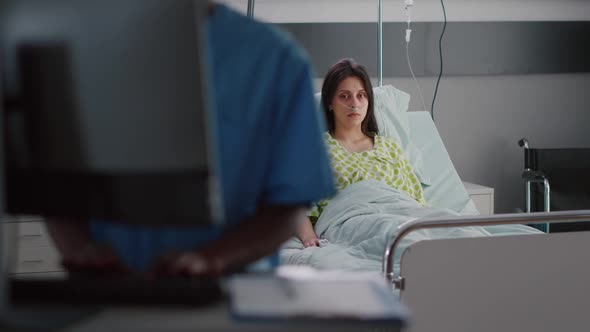 Front View of Sick Woman with Nasal Oxygen Tube Sitting in Bed Recovering