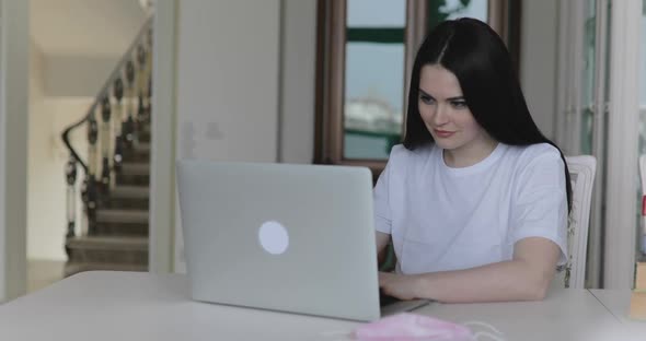 Successful Girl Working with Laptop and Smiling at Table Indoor