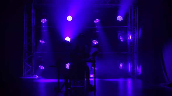 Male Drummer Musician Plays a Musical Instrument in a Dark Studio Against a Background of Blue