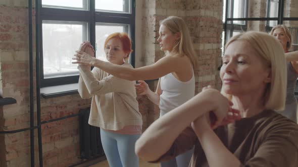 Mature Women Stretching on Yoga with Instructor